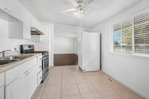 Kitchen with white cabinetry, gas stove, light countertops, and white refrigerator with ice dispenser