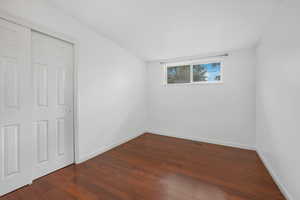 Unfurnished bedroom featuring dark wood finished floors and a closet