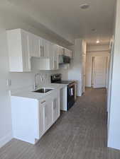 Kitchen featuring electric stove, white cabinetry, and dark wood-style flooring