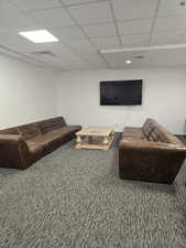 Club room with a paneled ceiling and carpet flooring,big screen tv.