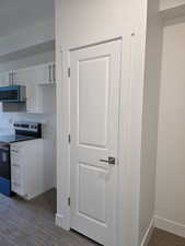 Kitchen Pantry with stainless steel appliances, white cabinetry, dark wood-style floors, and light countertops