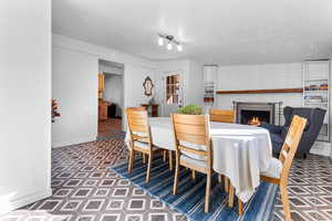 Dining area with a brick fireplace, a textured ceiling, and tile patterned floors