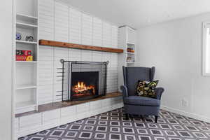 Sitting room featuring vaulted ceiling, a textured ceiling, a fireplace, built in shelves, and a textured wall