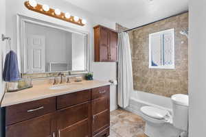 Full bathroom with vanity, shower / bath combo with shower curtain, and light tile patterned floors