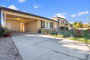 View of front facade with driveway, a carport, and brick siding