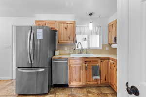 Kitchen with light countertops, appliances with stainless steel finishes, pendant lighting, and decorative backsplash