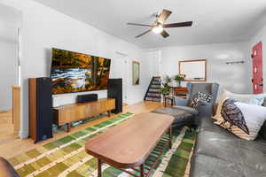 Living room with light wood-style flooring, stairway, and a ceiling fan