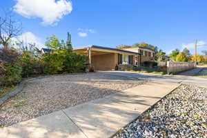 View of front facade with an attached carport, driveway, and brick siding
