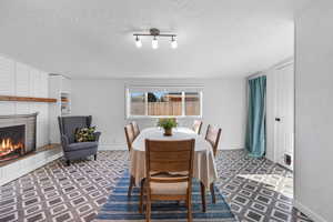 Dining area with a brick fireplace, tile patterned floors, and a textured ceiling