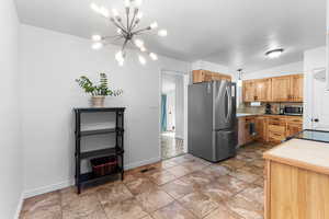 Kitchen featuring stainless steel appliances, light countertops, decorative backsplash, and a chandelier