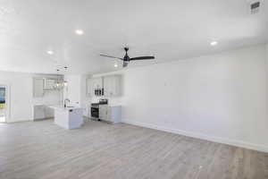 Kitchen with open floor plan, a kitchen island with sink, appliances with stainless steel finishes, light wood-type flooring, and recessed lighting