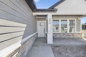 View of exterior entry featuring a porch and stone siding