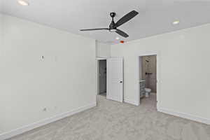 Unfurnished bedroom featuring light carpet, recessed lighting, ensuite bathroom, and a ceiling fan