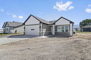 Ranch-style home featuring stone siding, driveway, and a garage
