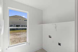 Laundry area featuring hookup for a washing machine, hookup for an electric dryer, and light tile patterned floors