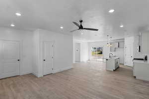 Unfurnished living room featuring light wood-style floors, recessed lighting, a textured ceiling, and a ceiling fan