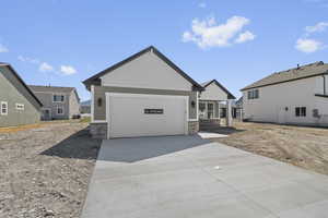 View of front of property featuring stone siding, driveway, and an attached garage