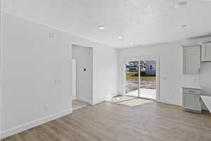 Unfurnished dining area featuring light wood-type flooring, recessed lighting, and a textured ceiling