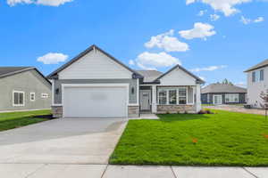 Craftsman inspired home featuring stone siding, concrete driveway, a front lawn, and an attached garage
