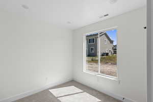 Carpeted spare room featuring baseboards