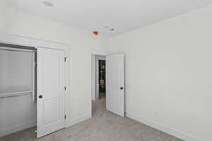 Unfurnished bedroom with light carpet and a closet