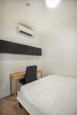 Bedroom featuring light wood finished floors and an AC wall unit