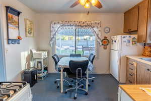 Dining space featuring ceiling fan, dark colored carpet, and a desk