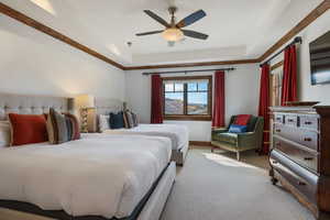 Carpeted bedroom featuring ceiling fan and a tray ceiling