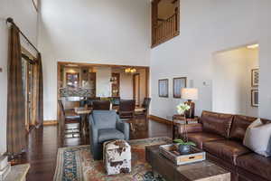 Living room with dark wood finished floors, a high ceiling, and a chandelier