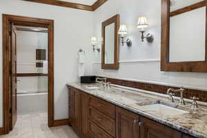 Full bath featuring double vanity, decorative backsplash, and light tile patterned flooring