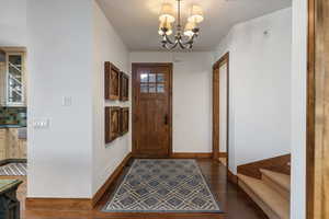 Entryway with a chandelier, dark wood finished floors, and stairway