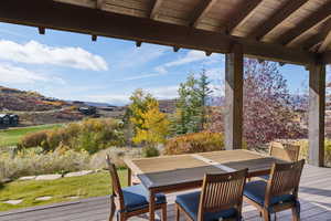 Wooden terrace with outdoor dining area, a mountain view, and a lawn