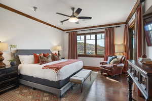 Bedroom with dark wood finished floors, ornamental molding, and ceiling fan
