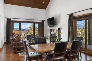 Dining space with wood ceiling, high vaulted ceiling, dark wood-style floors, and a fireplace
