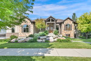 View of front of house featuring stone siding, a front yard, and brick siding