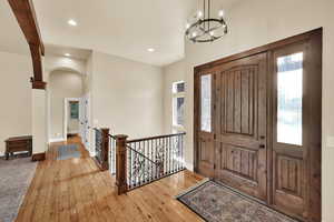 Foyer entrance featuring hardwood / wood-style floors, recessed lighting, arched walkways, and a chandelier