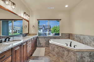 Full bath with double vanity, a bath, recessed lighting, and dark tile patterned flooring