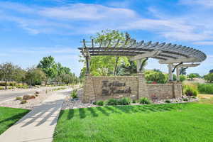 Community / neighborhood sign featuring a yard and a pergola