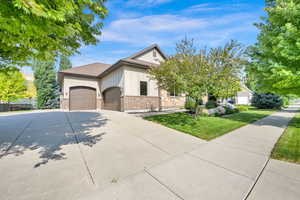 View of front of home with brick siding, a front yard, a garage, board and batten siding, and concrete driveway