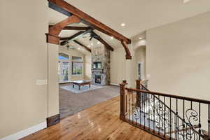Hallway featuring beam ceiling, light wood-style flooring, high vaulted ceiling, arched walkways, and recessed lighting