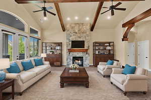 Carpeted living room featuring high vaulted ceiling, ceiling fan, a stone fireplace, beamed ceiling, and recessed lighting