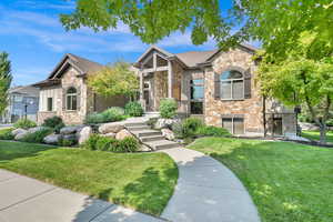 Craftsman-style house featuring a front yard, stone siding, and brick siding
