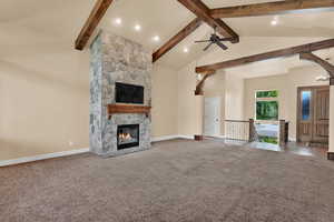 Unfurnished living room with carpet, beamed ceiling, a stone fireplace, high vaulted ceiling, and recessed lighting
