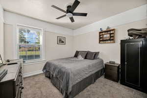 Bedroom with carpet floors, a textured ceiling, and ceiling fan