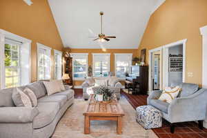 Tiled concrete flooring in living room featuring high vaulted ceiling and a ceiling fan