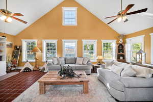 Tiled living room with a ceiling fan and high vaulted ceiling