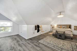 Bedroom featuring wood finished floors, lofted ceiling, and a textured ceiling