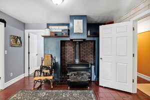 Transition area from entry to dining with a wood stove, a textured ceiling, and concrete tile flooring