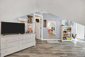 Bedroom with a textured ceiling, light wood finished floors, and vaulted ceiling