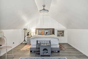 Bedroom with wood finished floors, a textured ceiling, and lofted ceiling